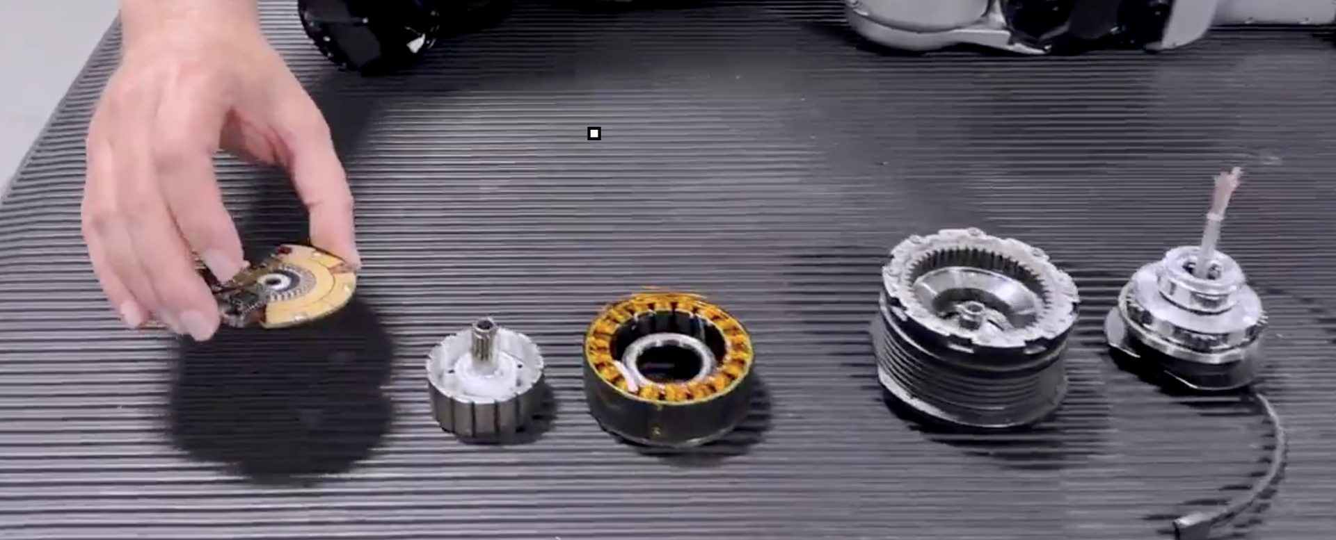 Five exploded parts of a Unitree G1 rotary actuator laid out left to right: encoder board, inner rotor, wound stator, finned planetary housing, assembled output.